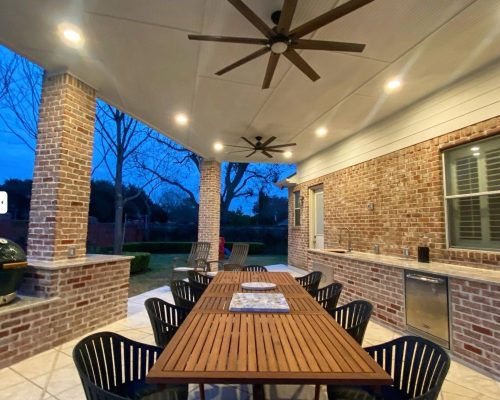 Outdoor living and kitchen area with a spacious deck, surrounded by lush greenery.
