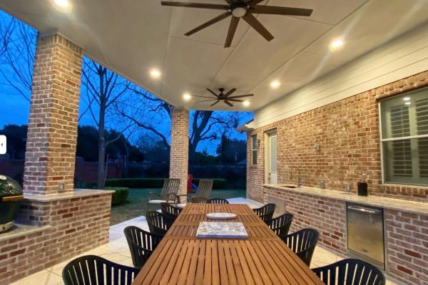 Outdoor living and kitchen area with a spacious deck, surrounded by lush greenery.