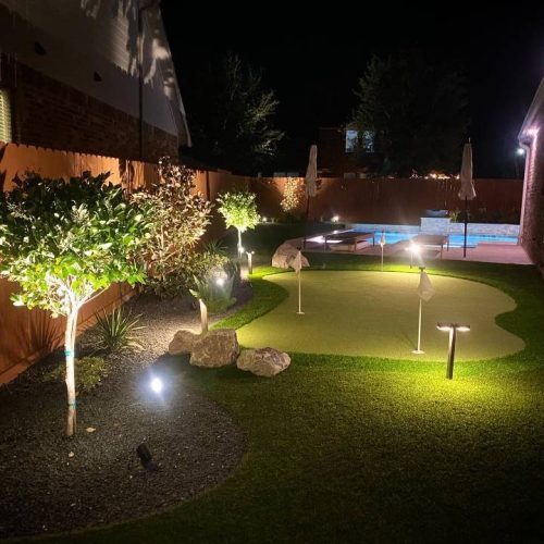 Image of a backyard with a vibrant green astroturf putting green.